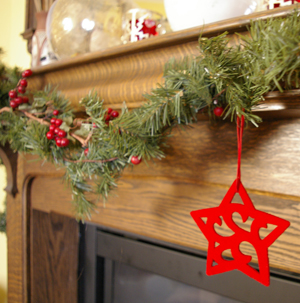 a felt star hanging from greenery at christmas in front of an antiqe oak mantle